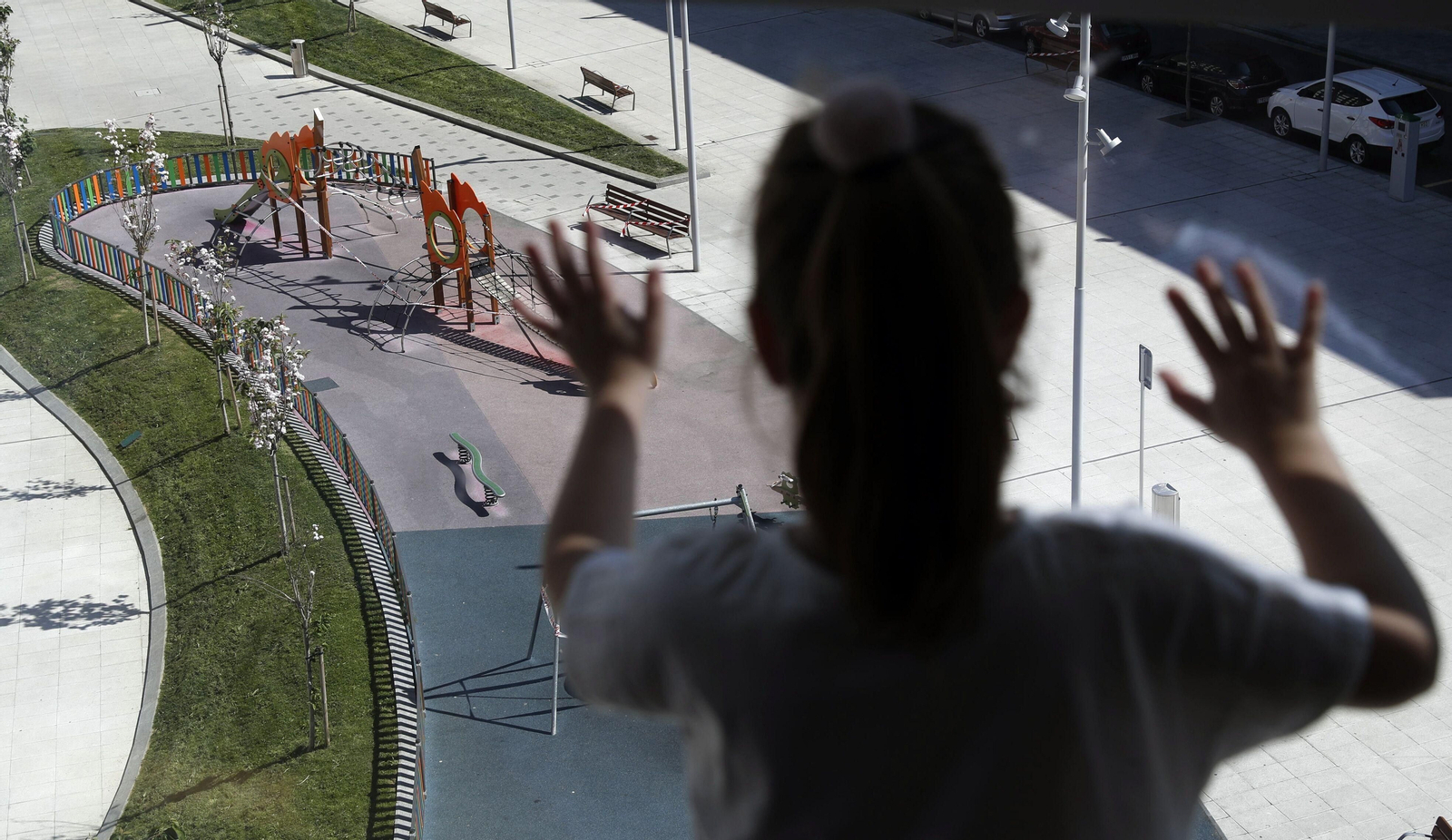 Una niña observa un parque desde una ventana.