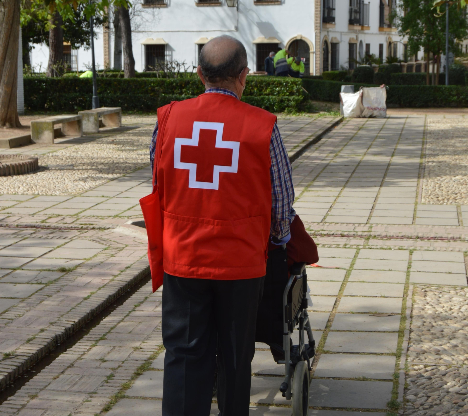 Un voluntario de Cruz Roja acompaña a una persona mayor.
