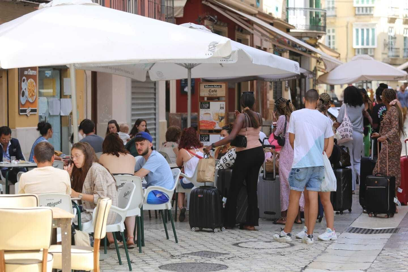 Un grupo de turistas con maletas junto a una terraza. Un grupo de turistas con maletas junto a una terraza.