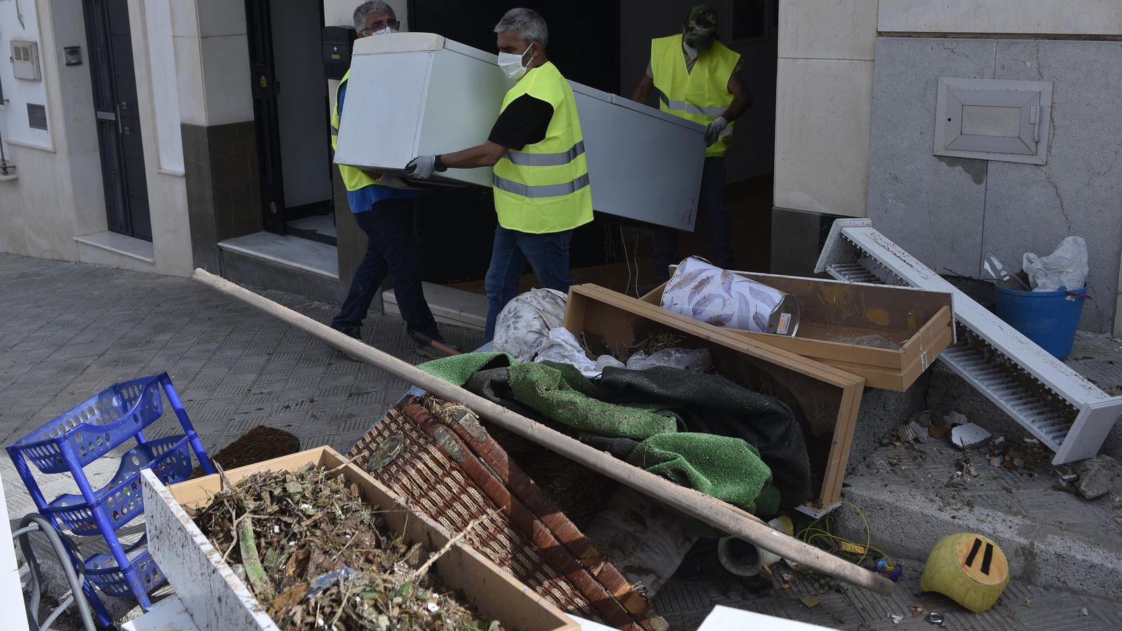 Varias personas sacan enseres dañados de una casa.