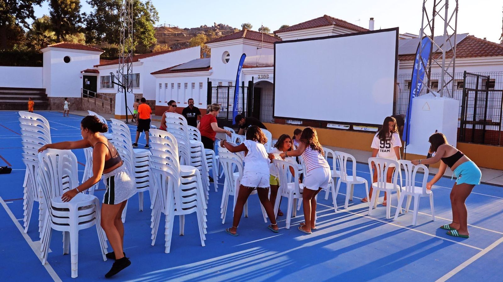 Vecinos colocan las sillas con ayuda de los más pequeños.