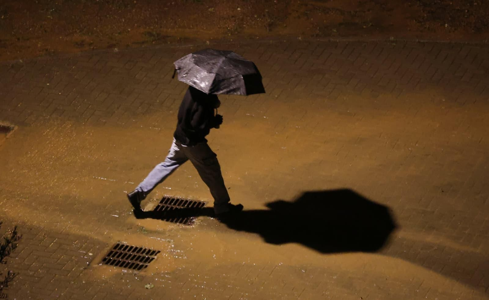 Un hombre se protege de la lluvia con un paraguas en Málaga en la noche de este viernes.