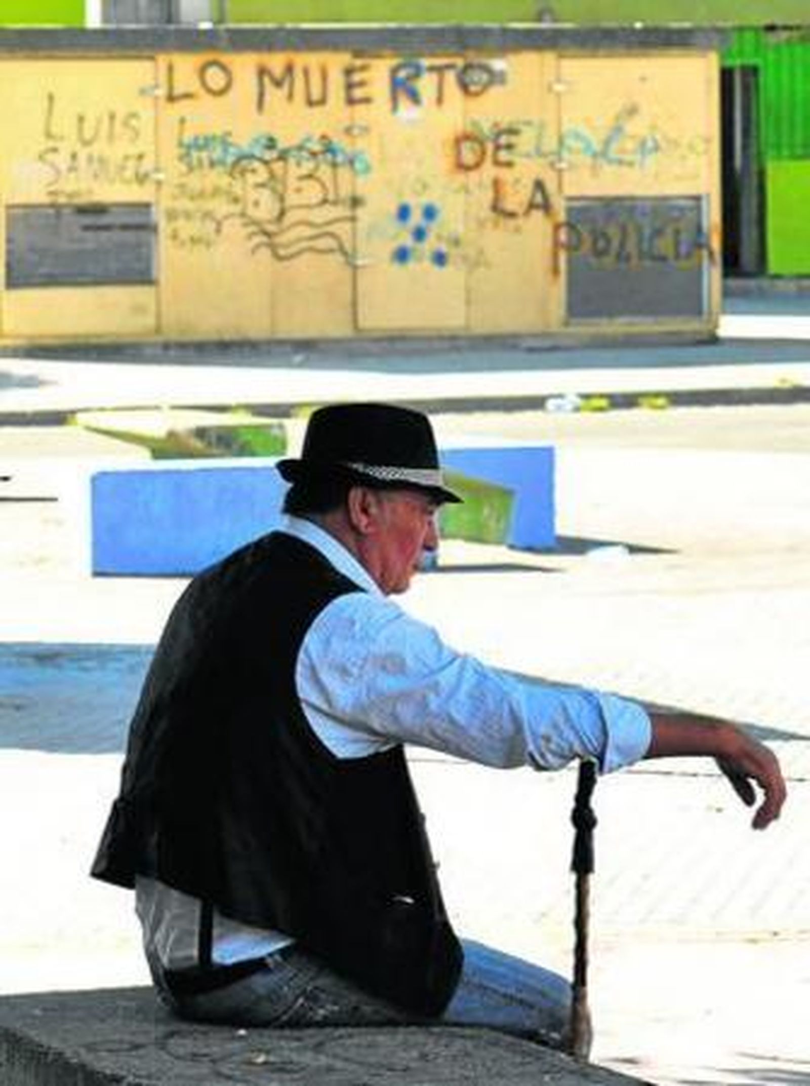 Un hombre pasa la mañana sentado en Las Vegas, donde al fondo se lee una pintada contra la Policía.