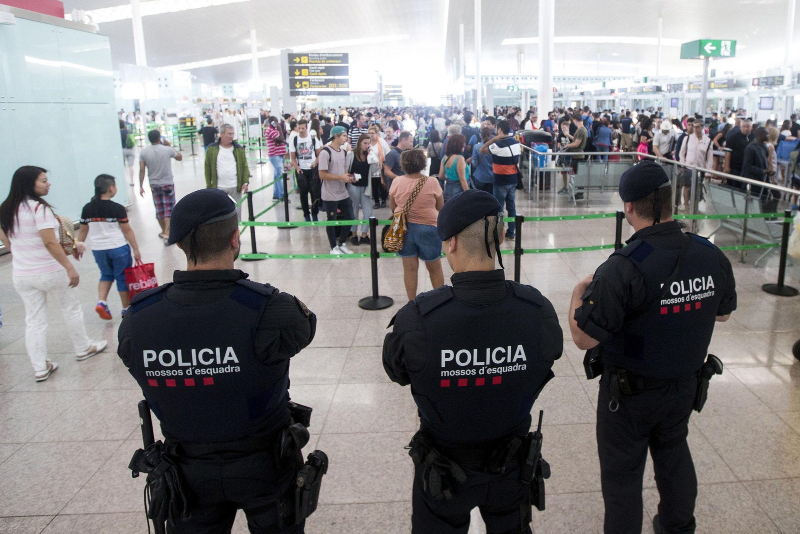 Agentes de los Mossos d'Esquadra controlan los accesos a las puertas de embarque en el Aeropuerto de El Prat.