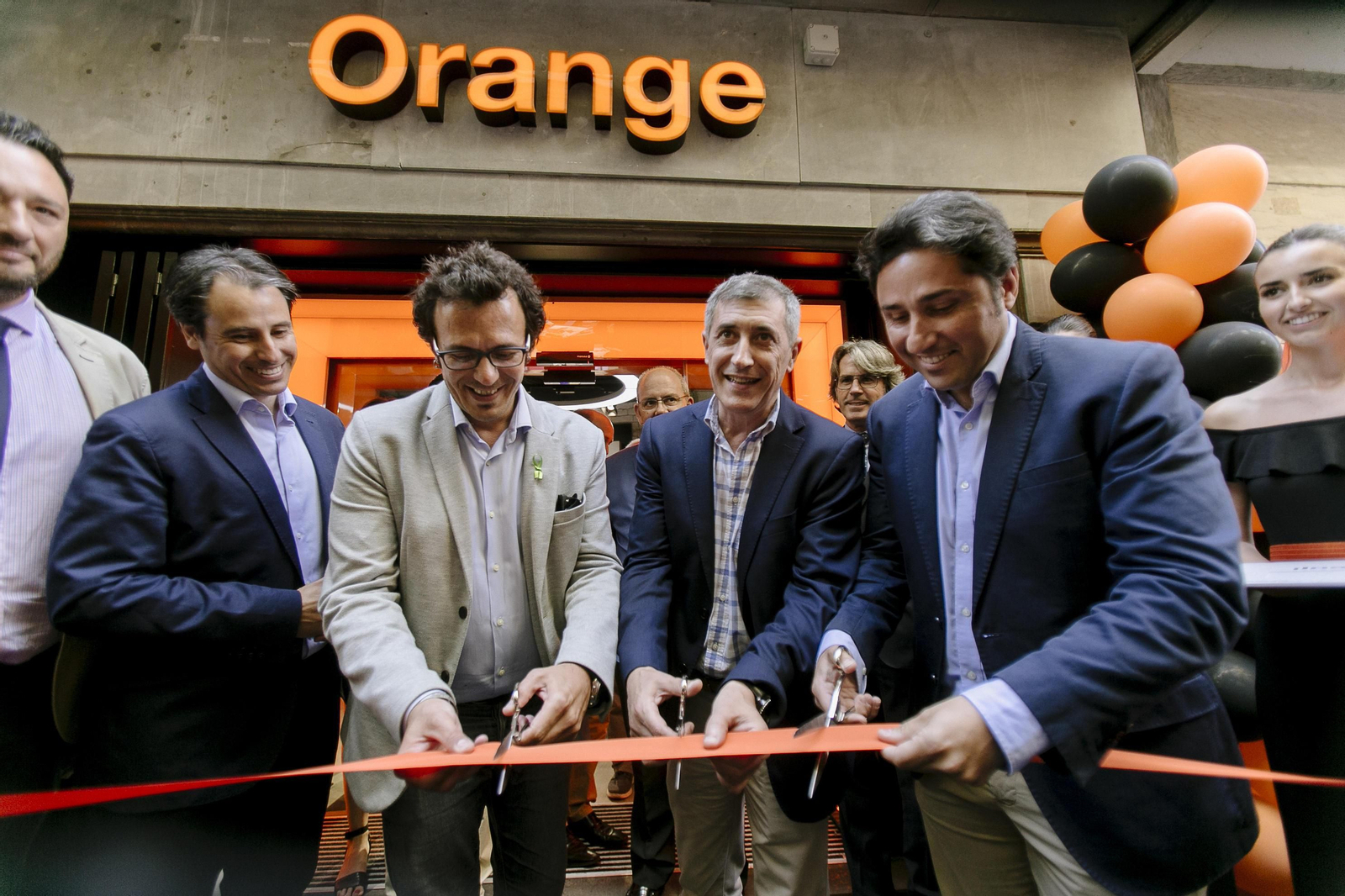 El alcalde, junto a directivos de Orange y los propietarios de la tienda, cortan la cinta de inauguración.