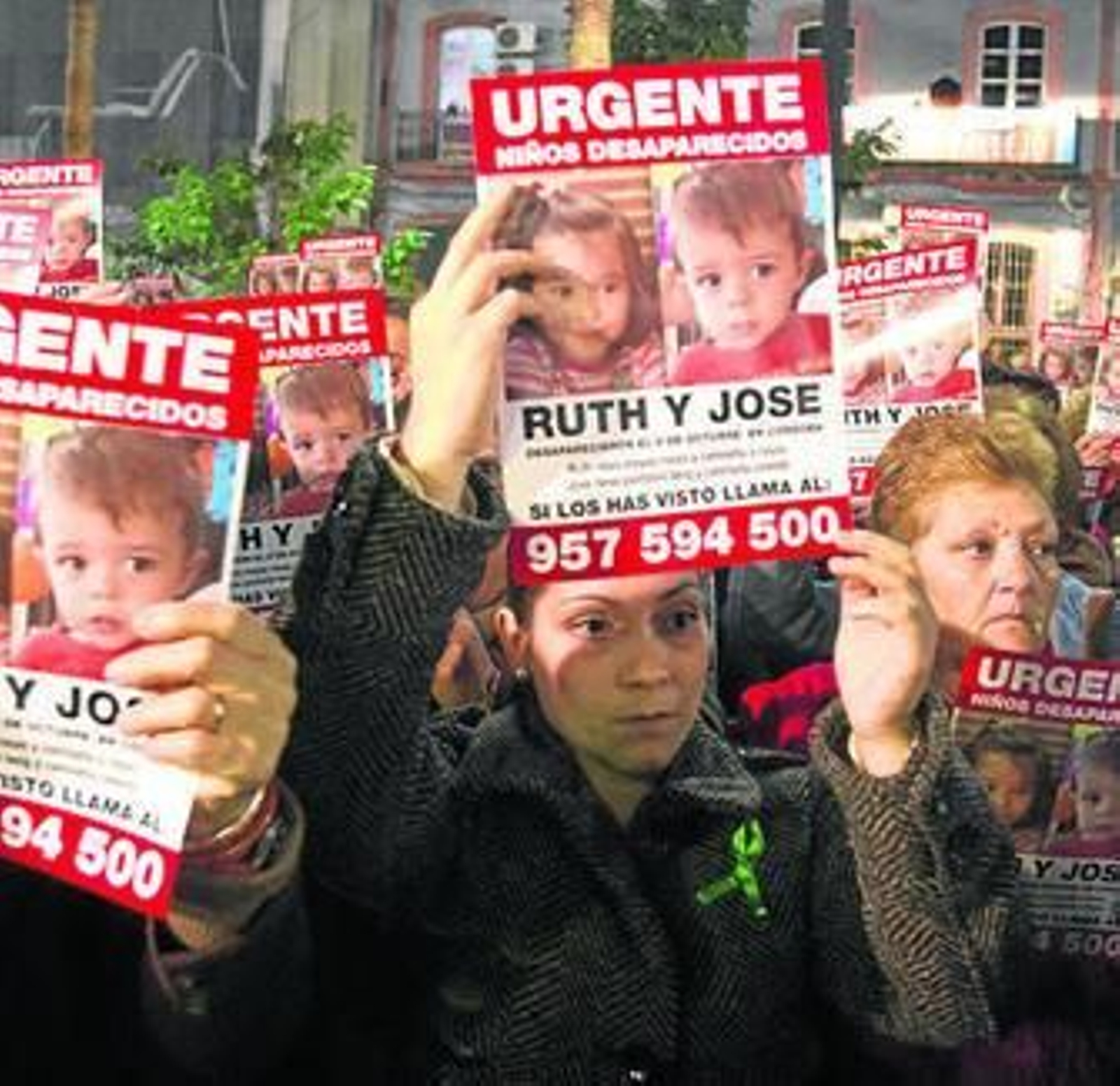 Varias personas sostienen carteles con la foto de los niños.