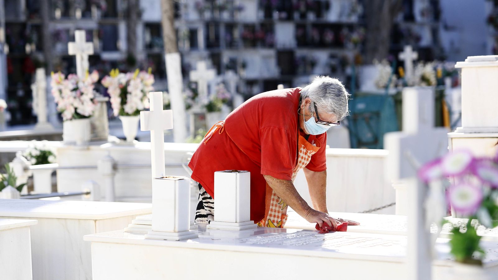 Una mujer limpia la tumba de un ser querido.
