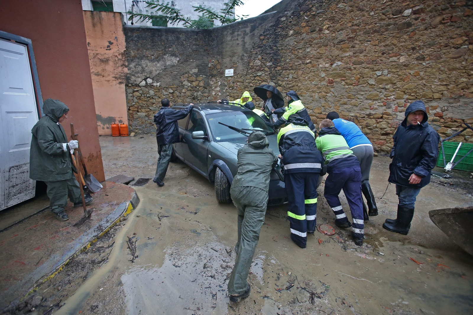 Varias personas empujan un coche durante el temporal en la Estación de San Roque.