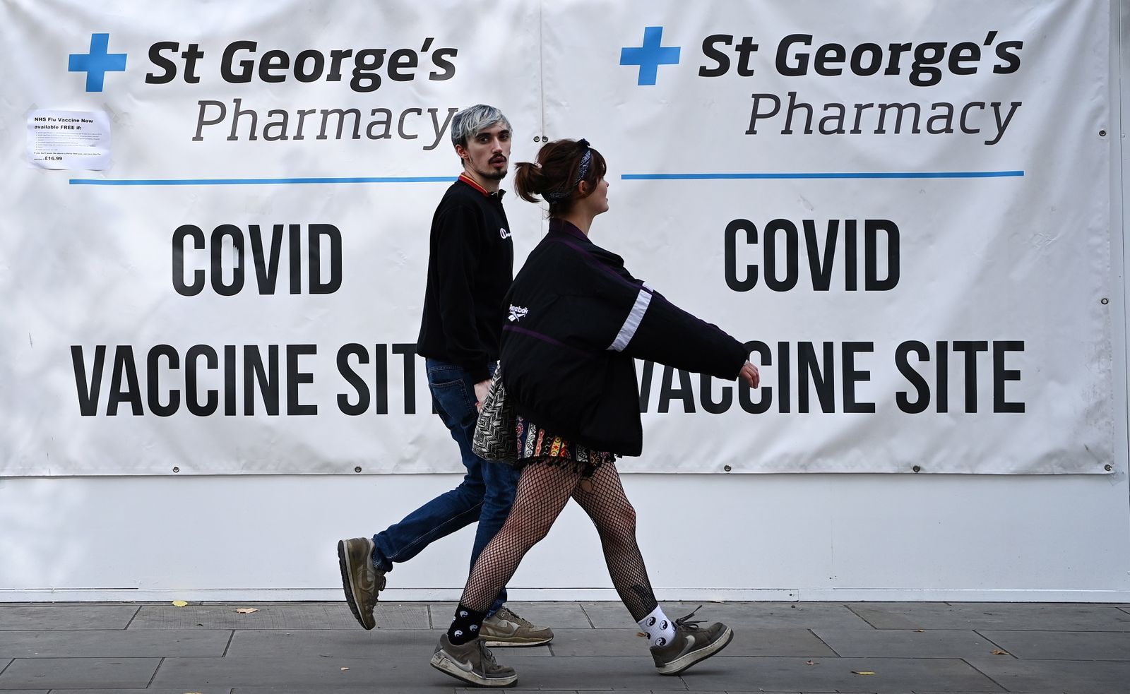Dos jóvenes pasan caminando ante un centro de vacunación, ayer en Londres.