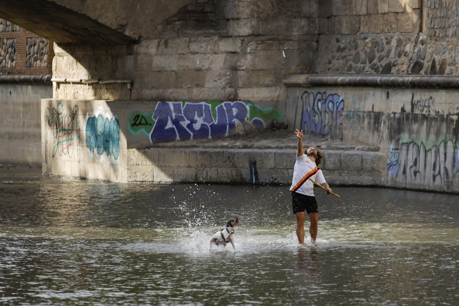 Un hombre juega con su perro en el río