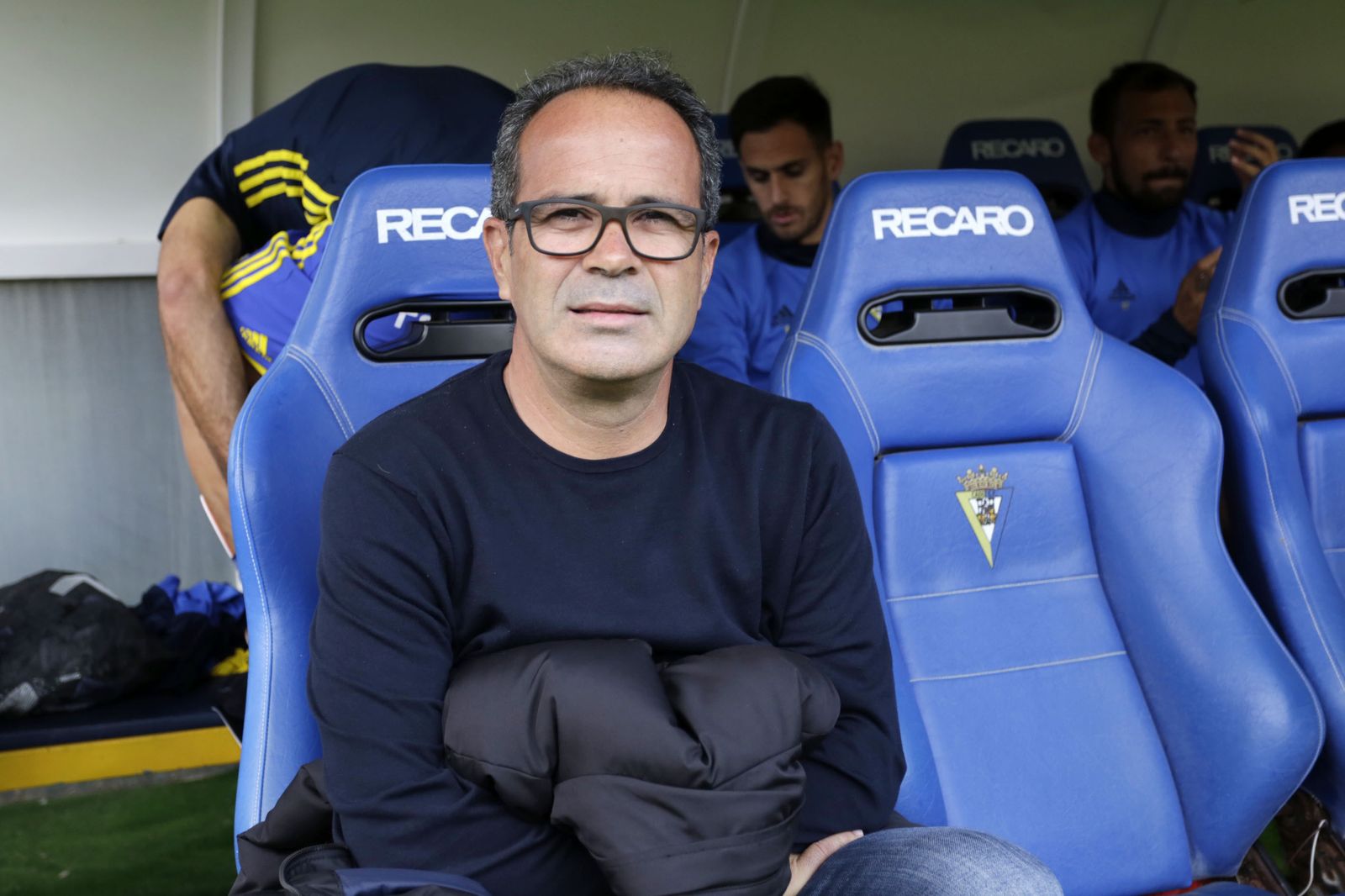 Leve sonrisa de Cervera mientras espera sentado en el banquillo el inicio del encuentro.