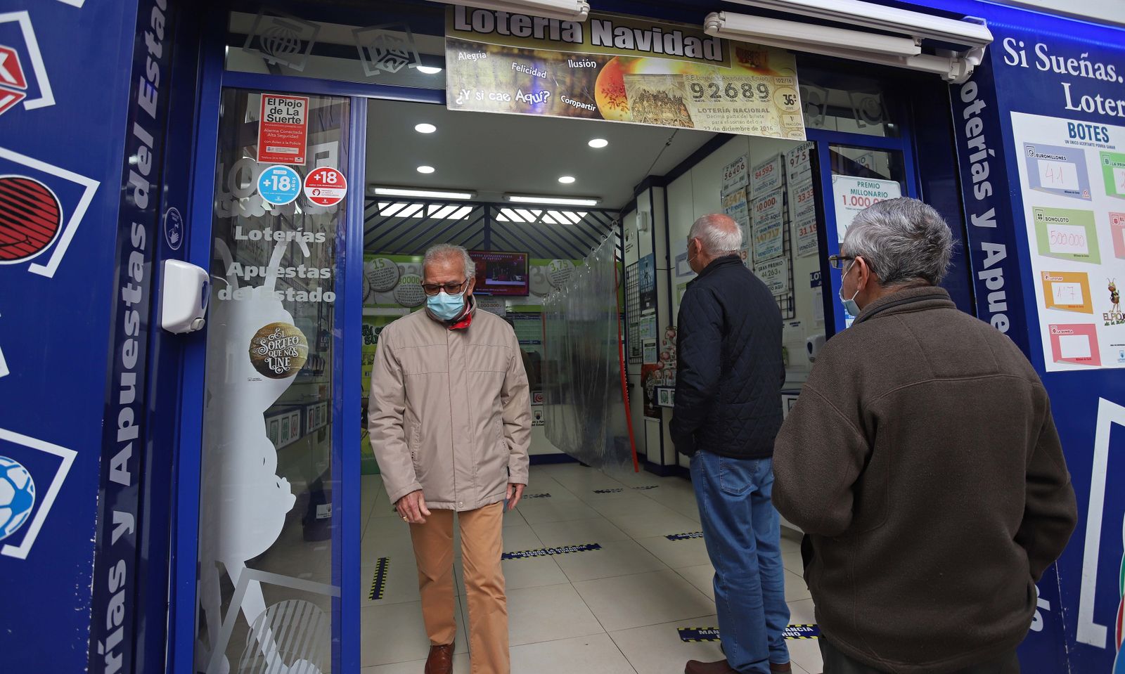 Clientes guardando cola en una administración de lotería.