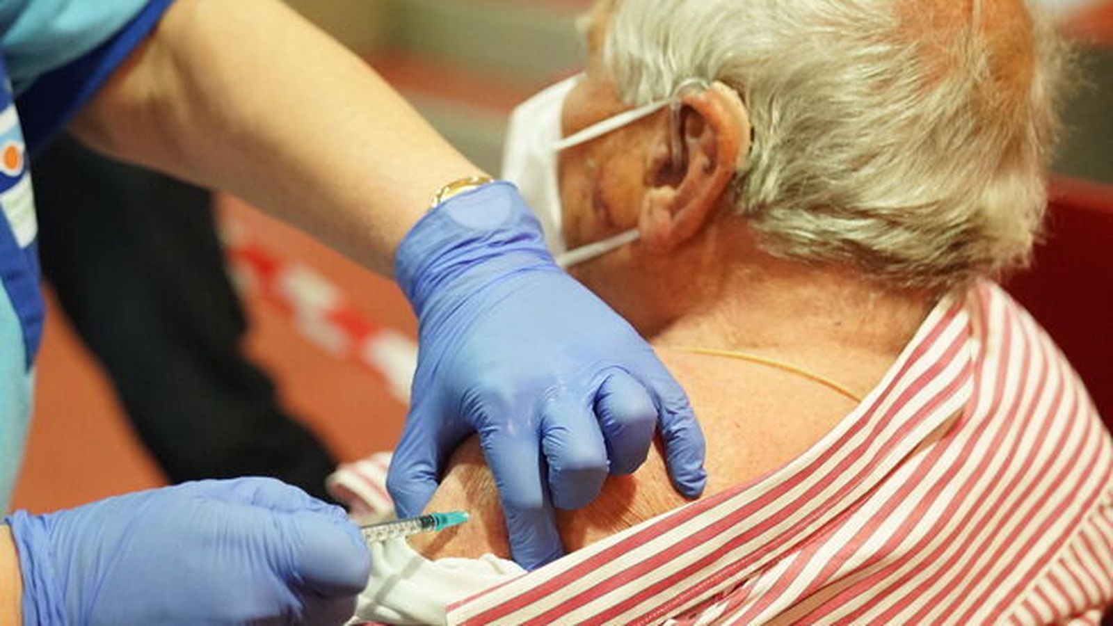Una enfermera vacunando a un anciano en una residencia