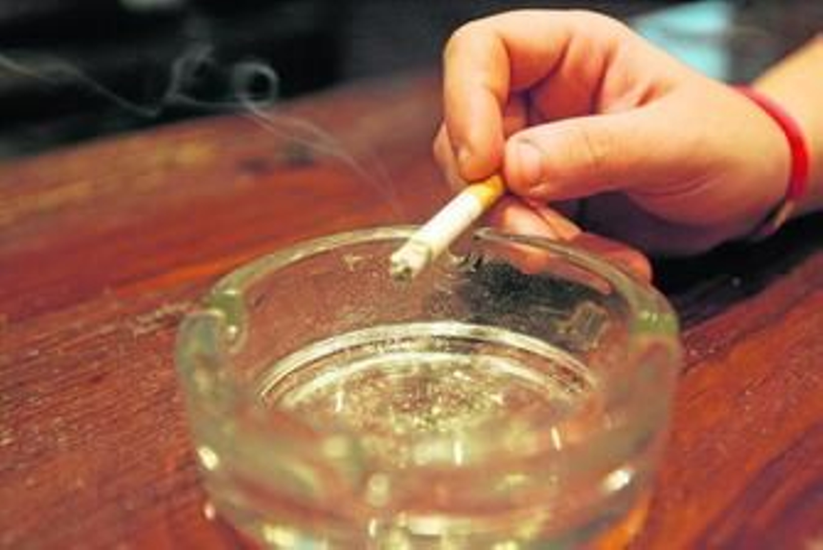 Un cigarro en las manos de un fumador y un cenicero. Un cigarro en las manos de un fumador y un cenicero.
