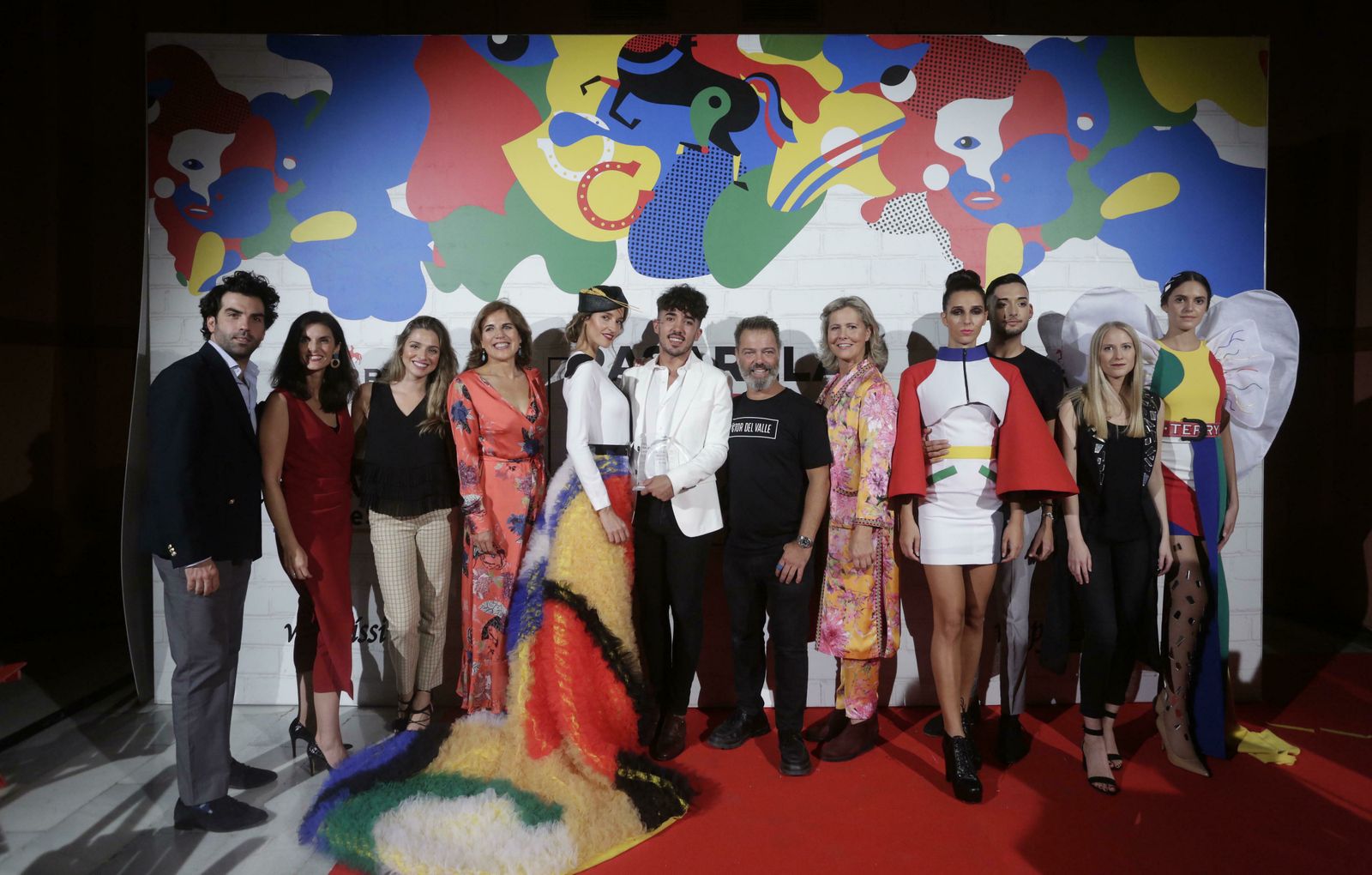 De izquierda a derecha: Felipe Muñoz, Social Medial Mánager de Flamentex,; María Maldonado, Directora de Wappíssima; Mamen Sánchez, Marketing de Grupo Emperador; Victoria Herrera, Directora Comercial de Grupo Joly; el ganador del primer premio Tom Márquez posando con la modelo que lleva su diseño; el estilista Víctor del Valle; la diseñadora  y madrina del evento Rosa León; el segundo finalista Adrián Mesa posando con la modelo que lleva su diseño; y la tercera finalista, Andrea Fernández con la modelo que posa con su propuesta.