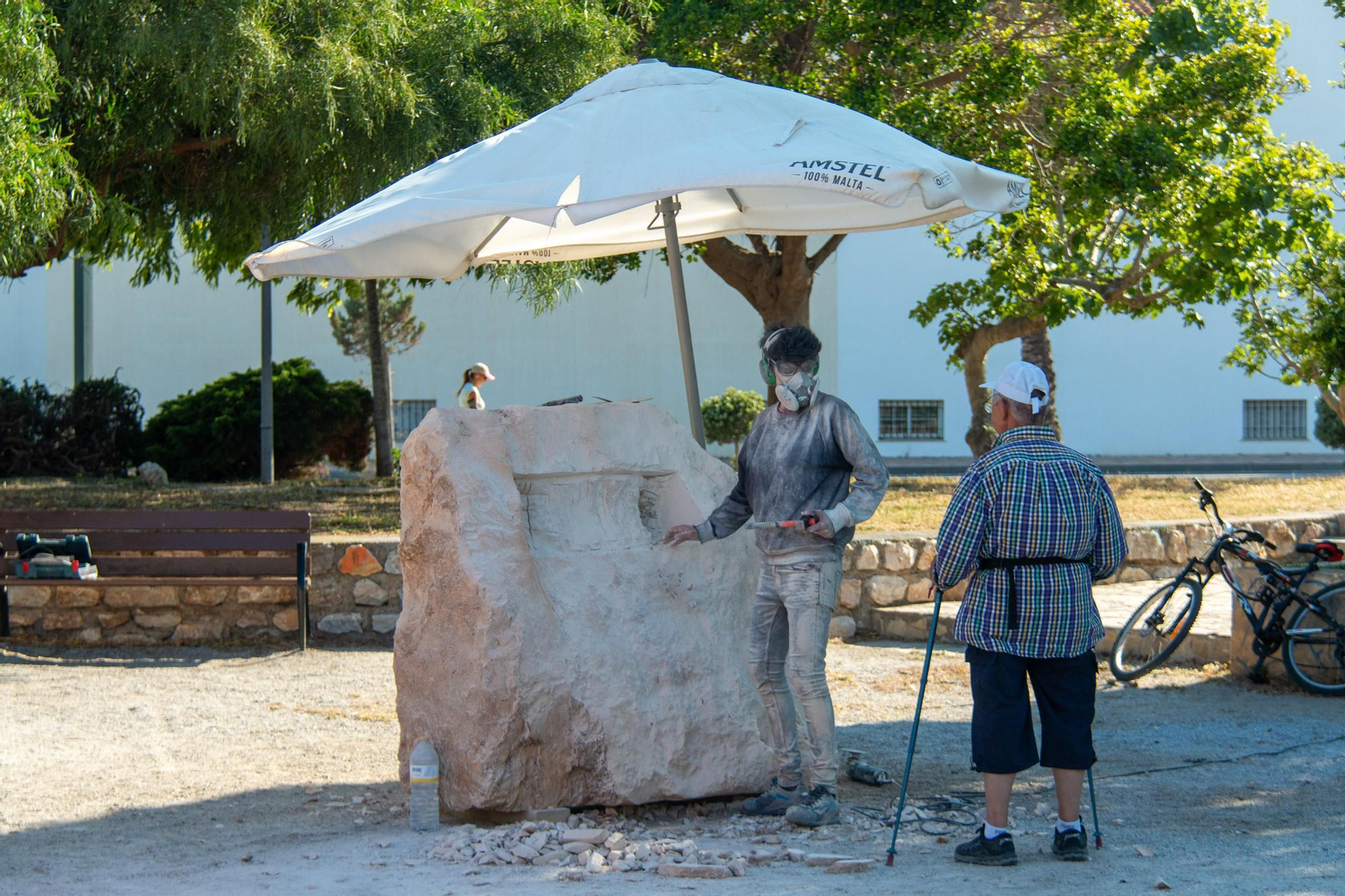 Un hombre observa a una de las artistas comenzar a esculpir la piedra