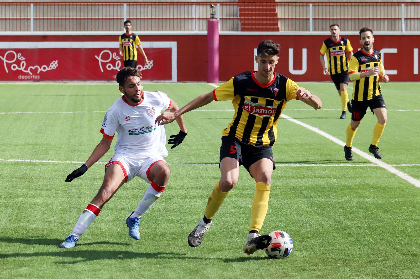 Antonio López controla el cuero ante la presión de un jugador local.