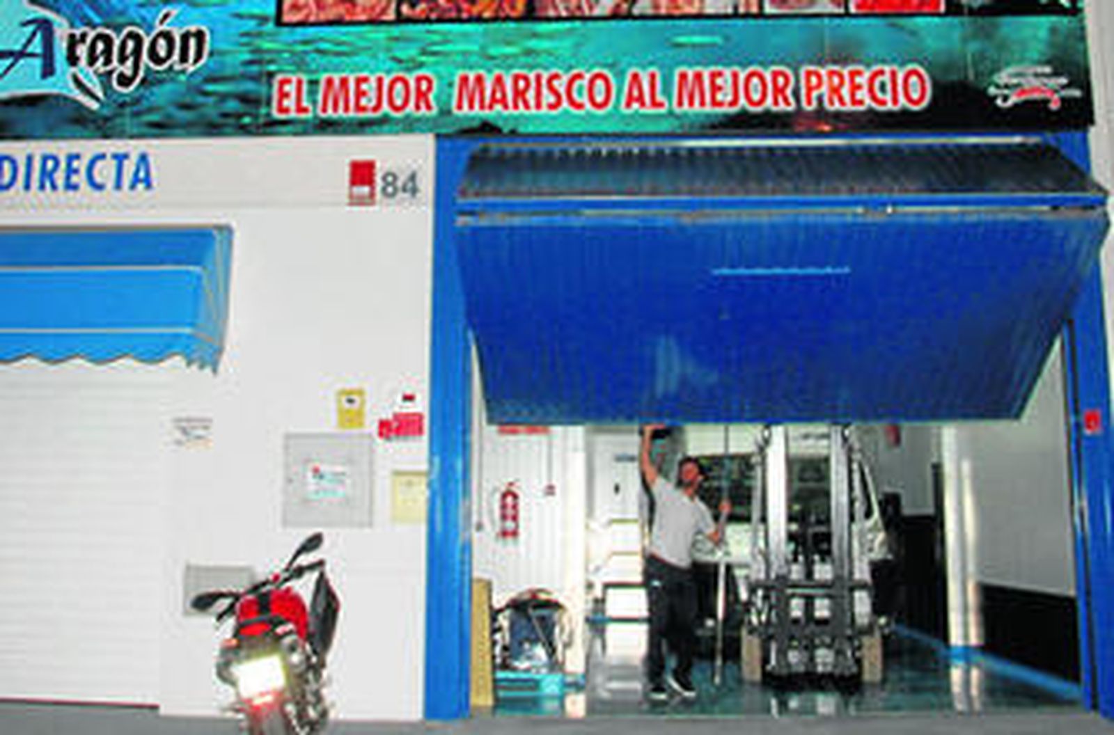 Un empleado en la puerta de Pescados y Mariscos Aragón, en el polígono La Zorrera, en Conil.