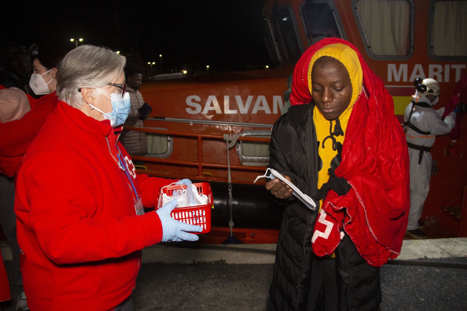 Un voluntario de Cruz Roja atienda a una migrante tras desembarcar en el Puerto de Motril