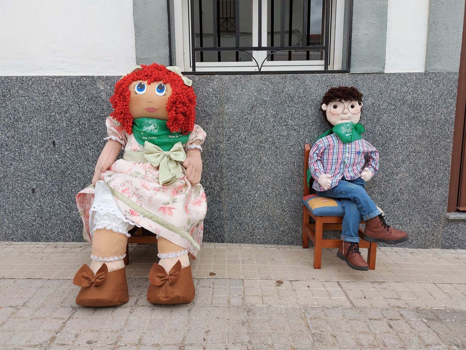 Muñecas de la más variada índole esperan el paso de los vecinos a las puertas de la casas en Cardeña