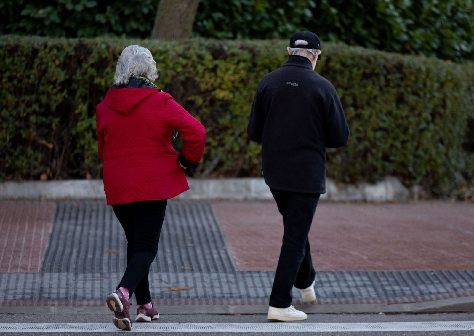 Dos personas mayores caminan por la calle.