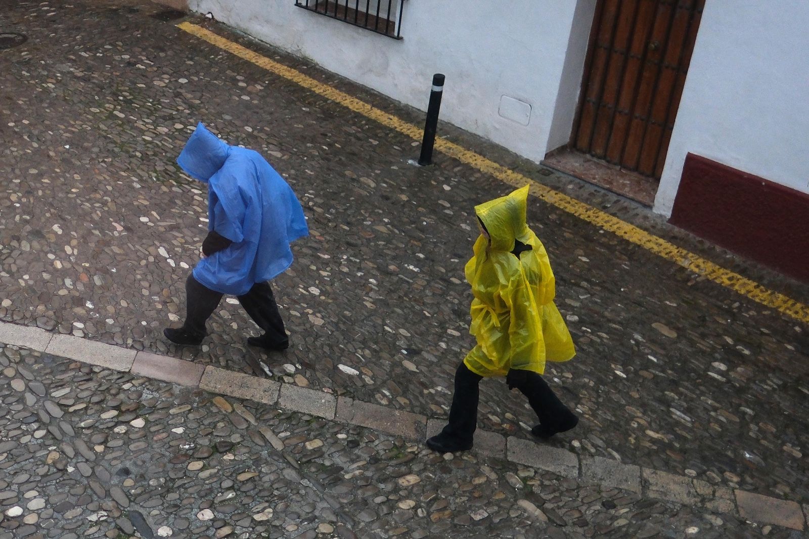Dos personas se protegen de la lluvia con chubasqueros.