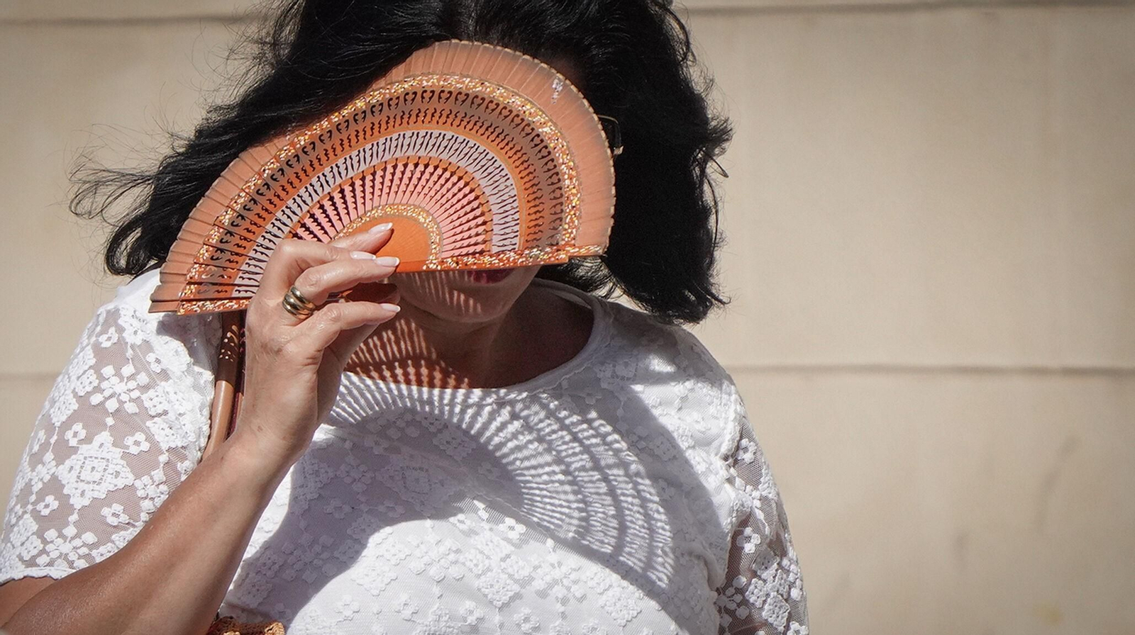 Una mujer se protege del sol con un abanico esta tarde en el centro de Jerez.