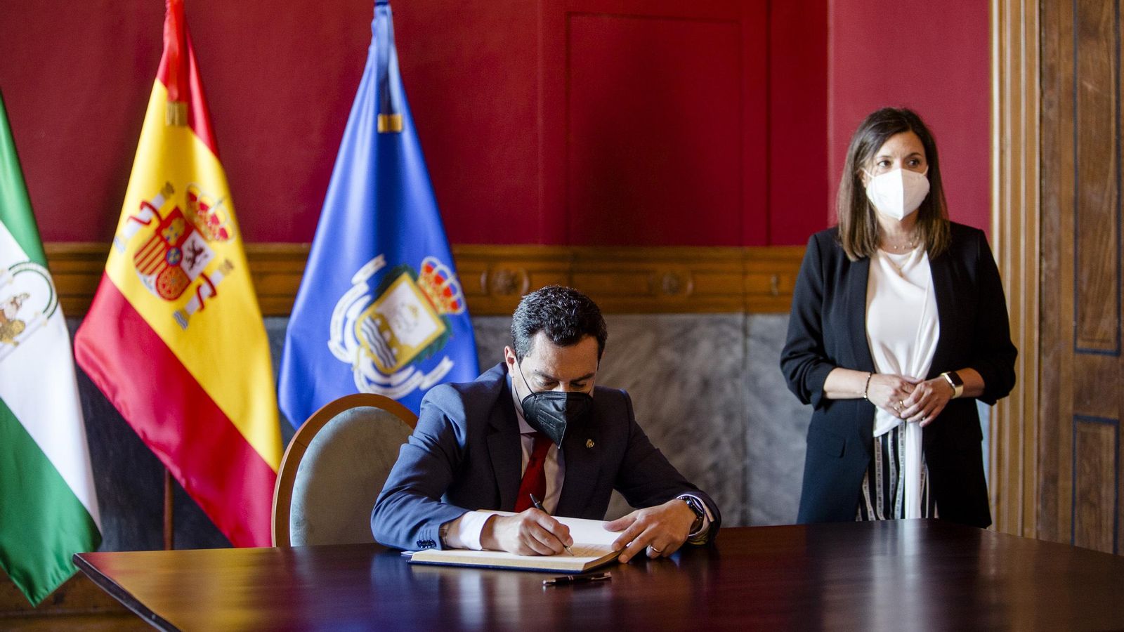 Juanma Moreno firma en el libro de honor del Ayuntamiento isleño.