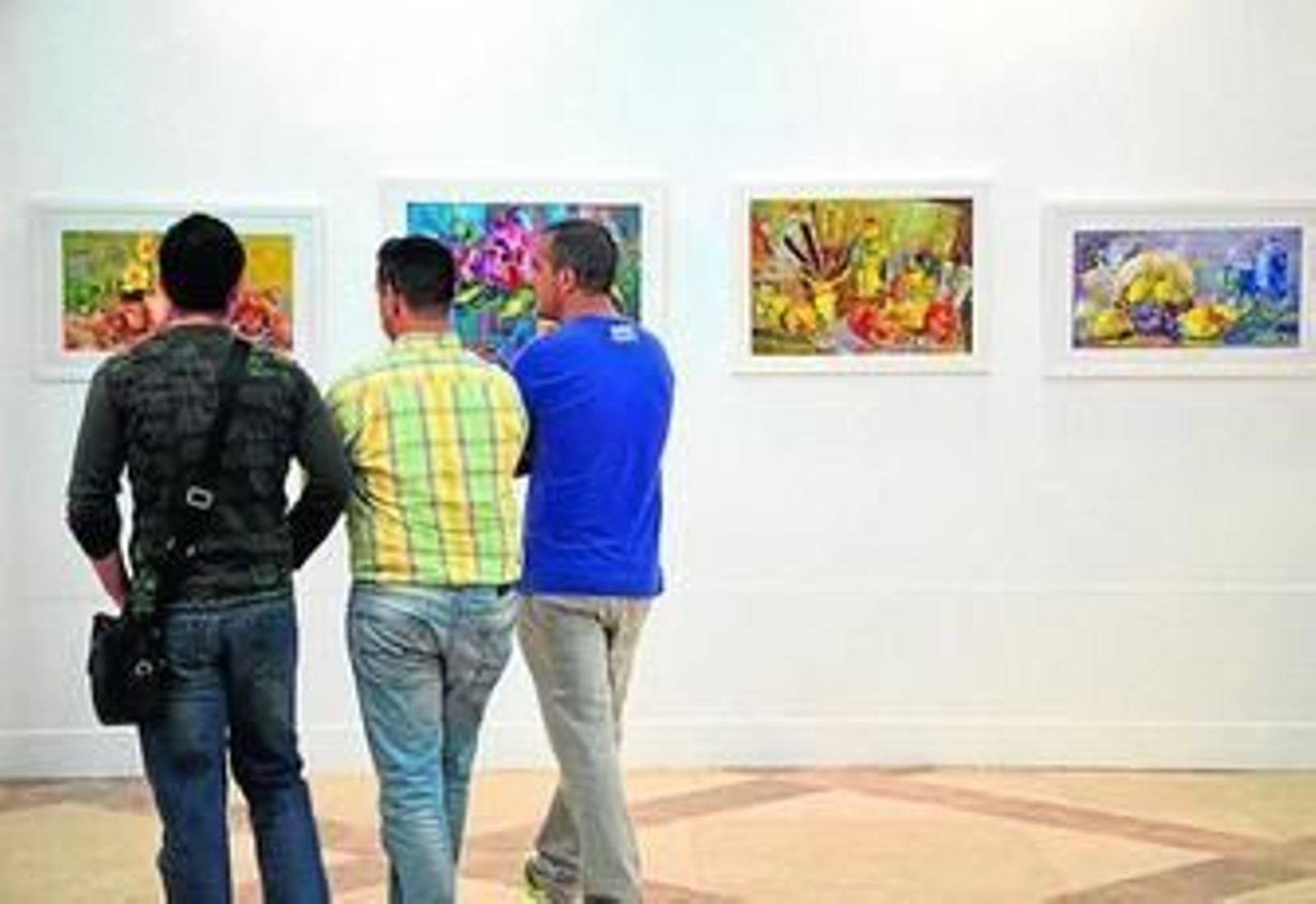 Tres jóvenes miran algunas de las obras realizadas por Lola Guzmán.