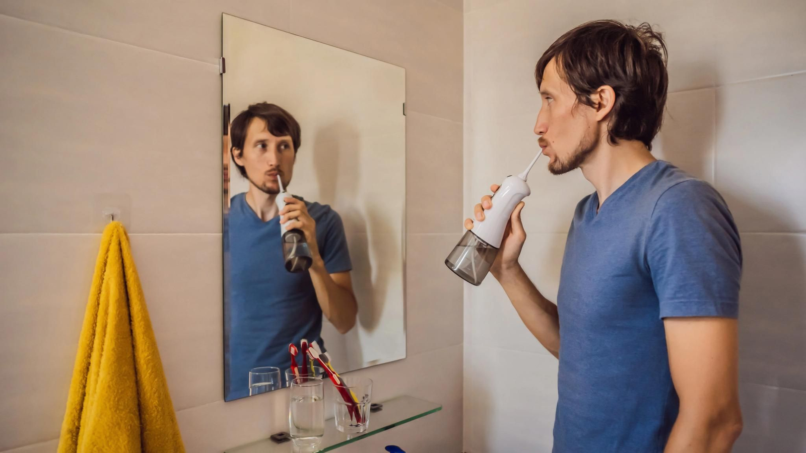 Un hombre usa el irrigador bucal después del cepillado