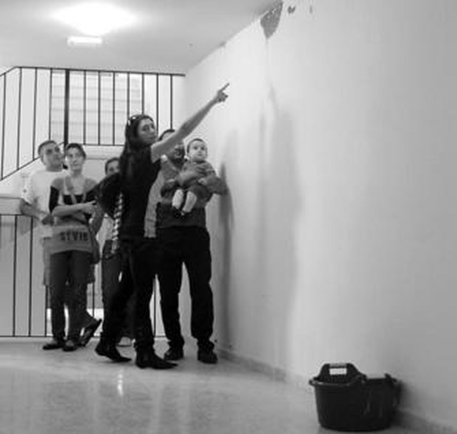 Vecinos muestran las grietas del bloque y los cubos que recogen el agua de las goteras.