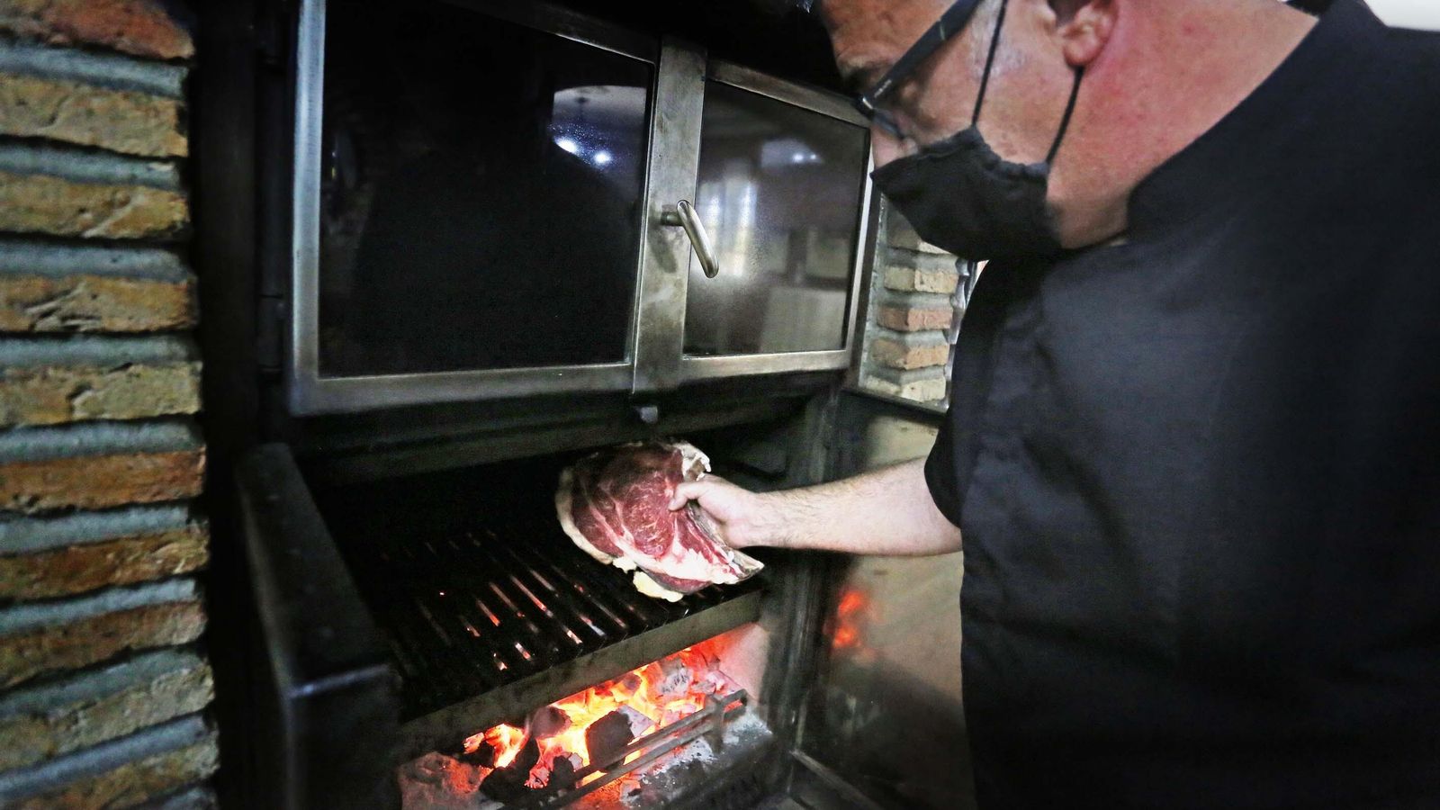 El propietario del Restaurante-Venta Gabriel de Cuartillos se dispone a echar un chuletón a las brasas.