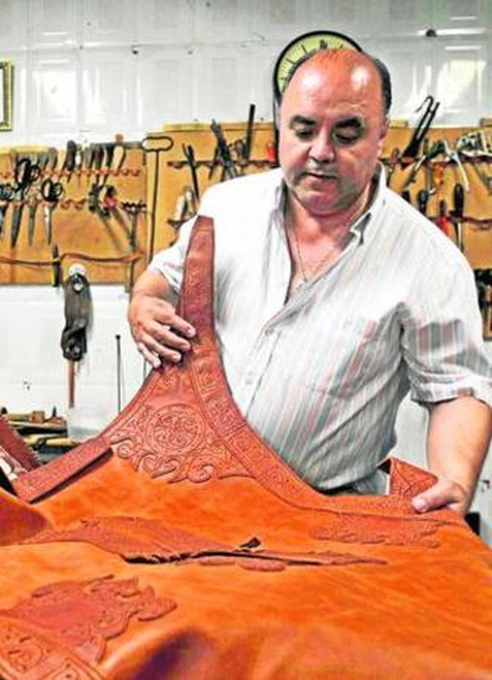 El guarnicionero Juan Vega en su taller, mostrando una de sus obras.
