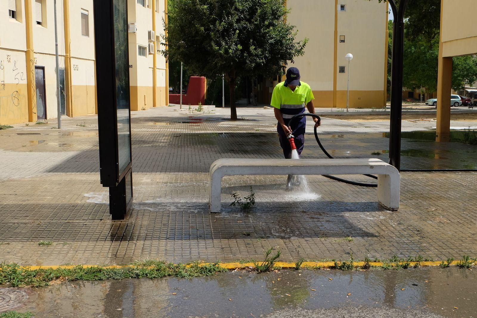 Un operario limpia con agua a presión una parada de autobús
