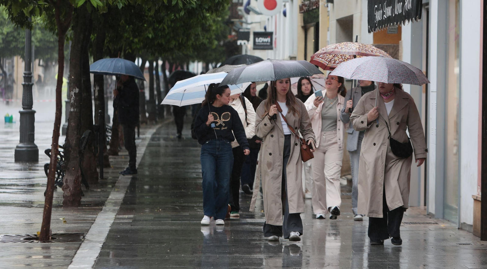 Varias personas caminan mientras llueve por la calle Larga
