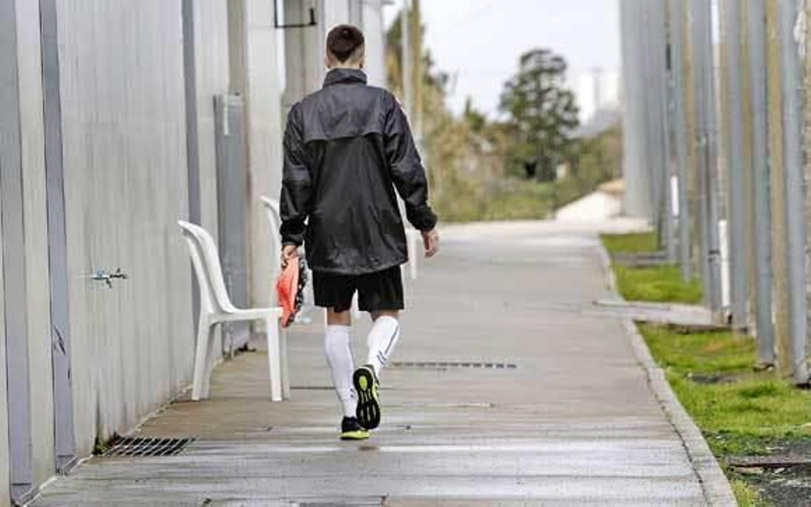Salvi sujeta sus botas con la mano izquierda mientras camina en solitario junto a los campos de césped artificial de El Rosal. /Fito Carreto