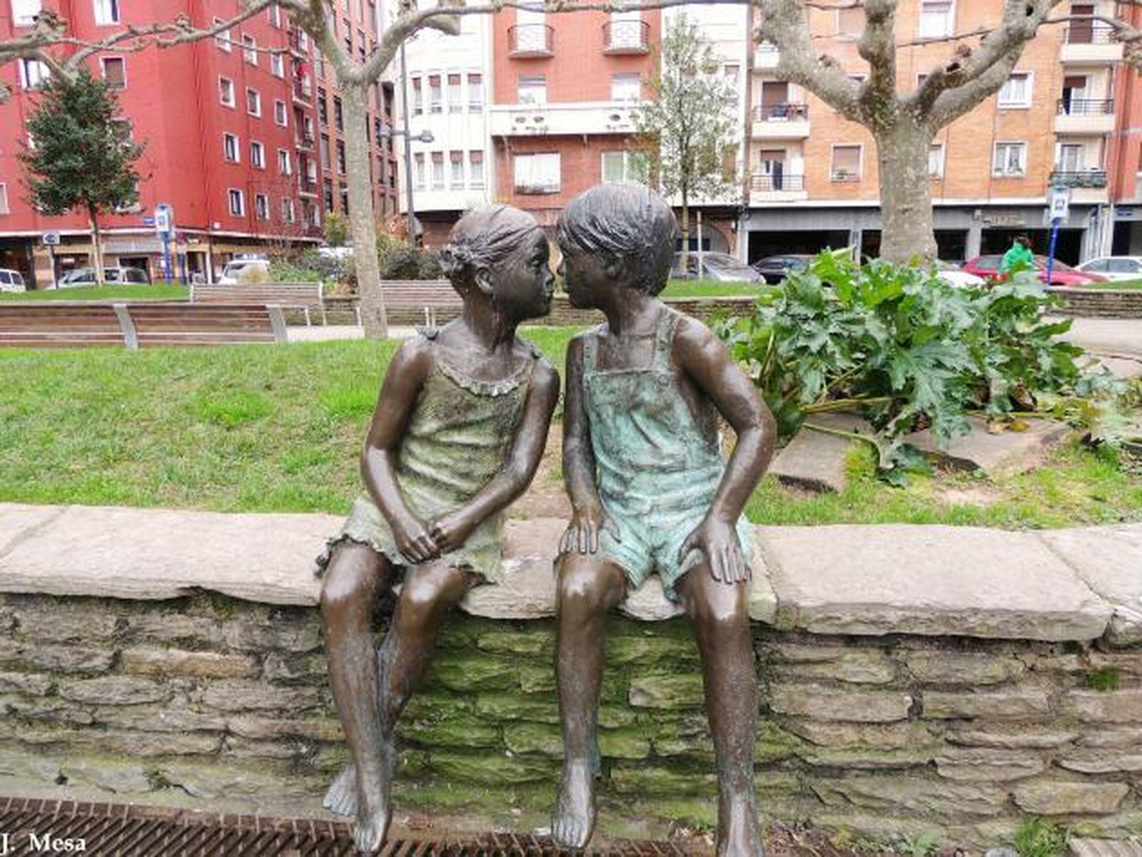 Una estatua de dos niños sentados en un banco.