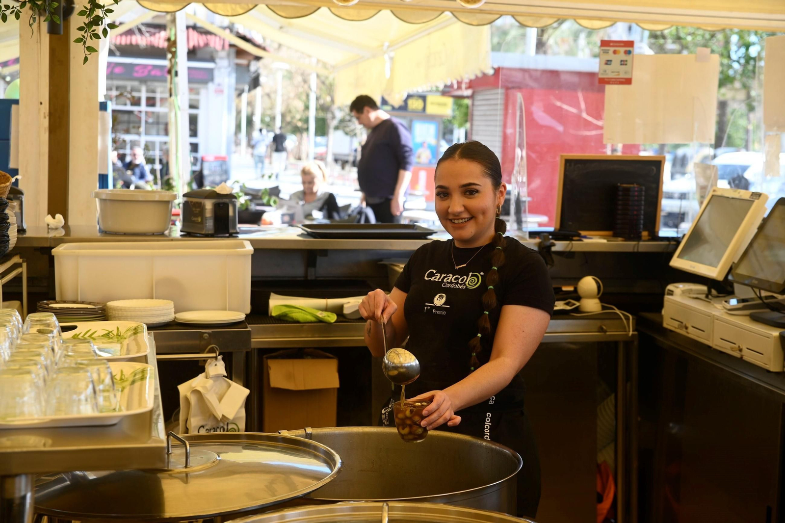 Una joven prepara un vaso de caracoles en un puesto