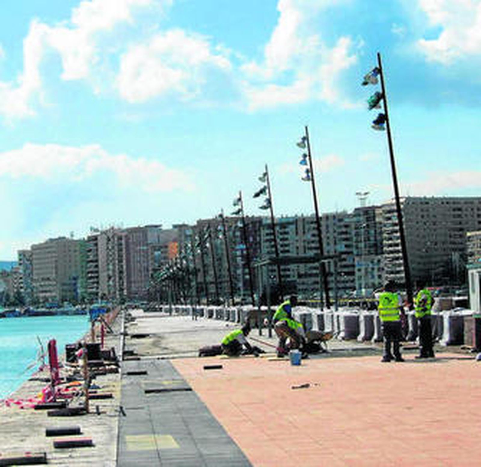 Operarios colocan baldosas en el nuevo Muelle de Ribera.