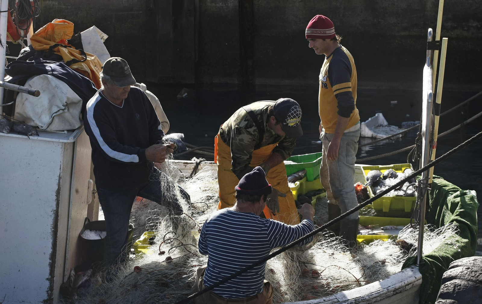 Varios pescadores repasan las redes a bordo de un pesquero en el puerto de Tarifa.