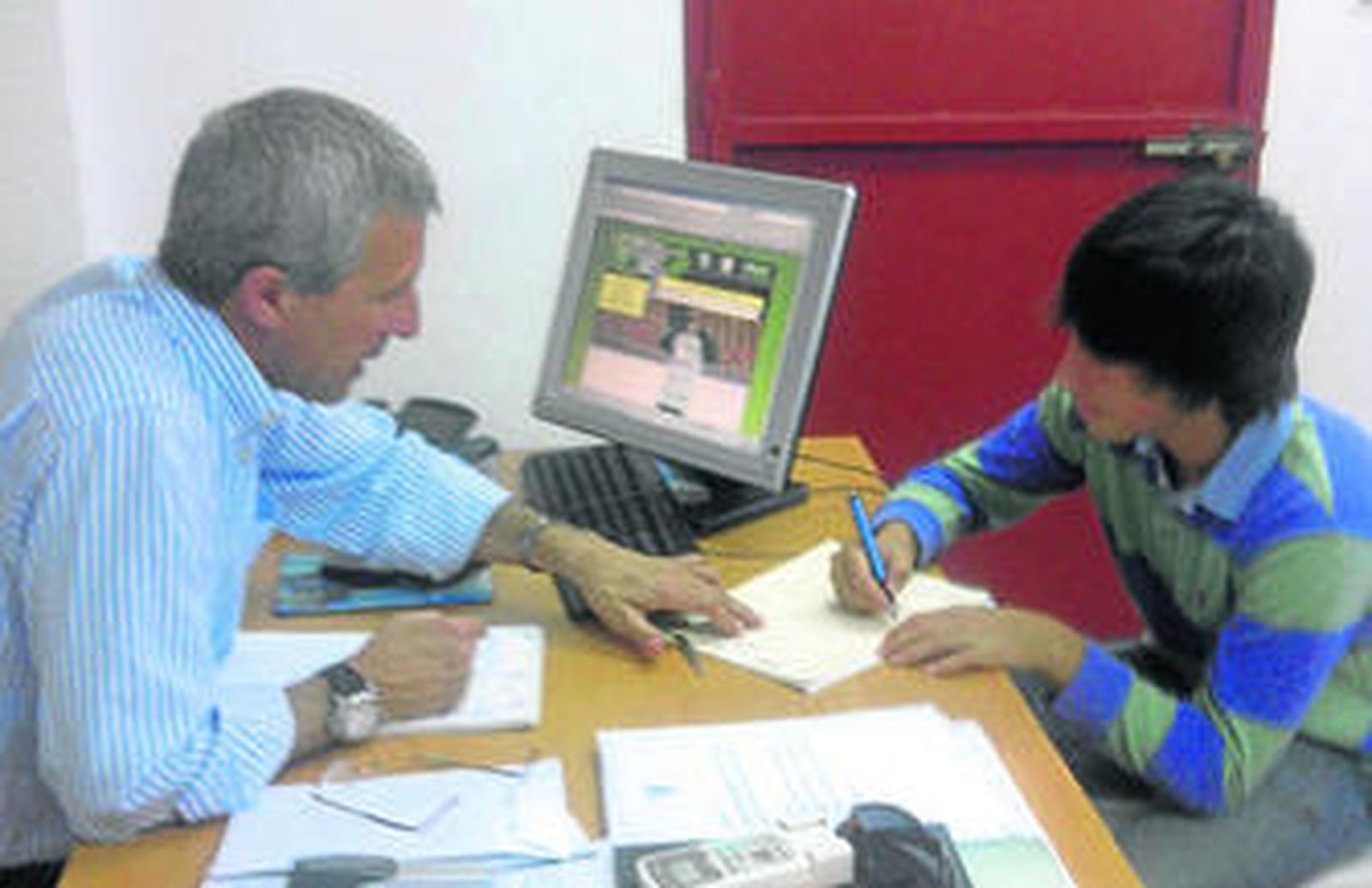 Pablo Acosta firma, ante Pablo Blanco, su contrato con el Sevilla. Abajo posa con el chándal de la equipación de su nuevo equipo.