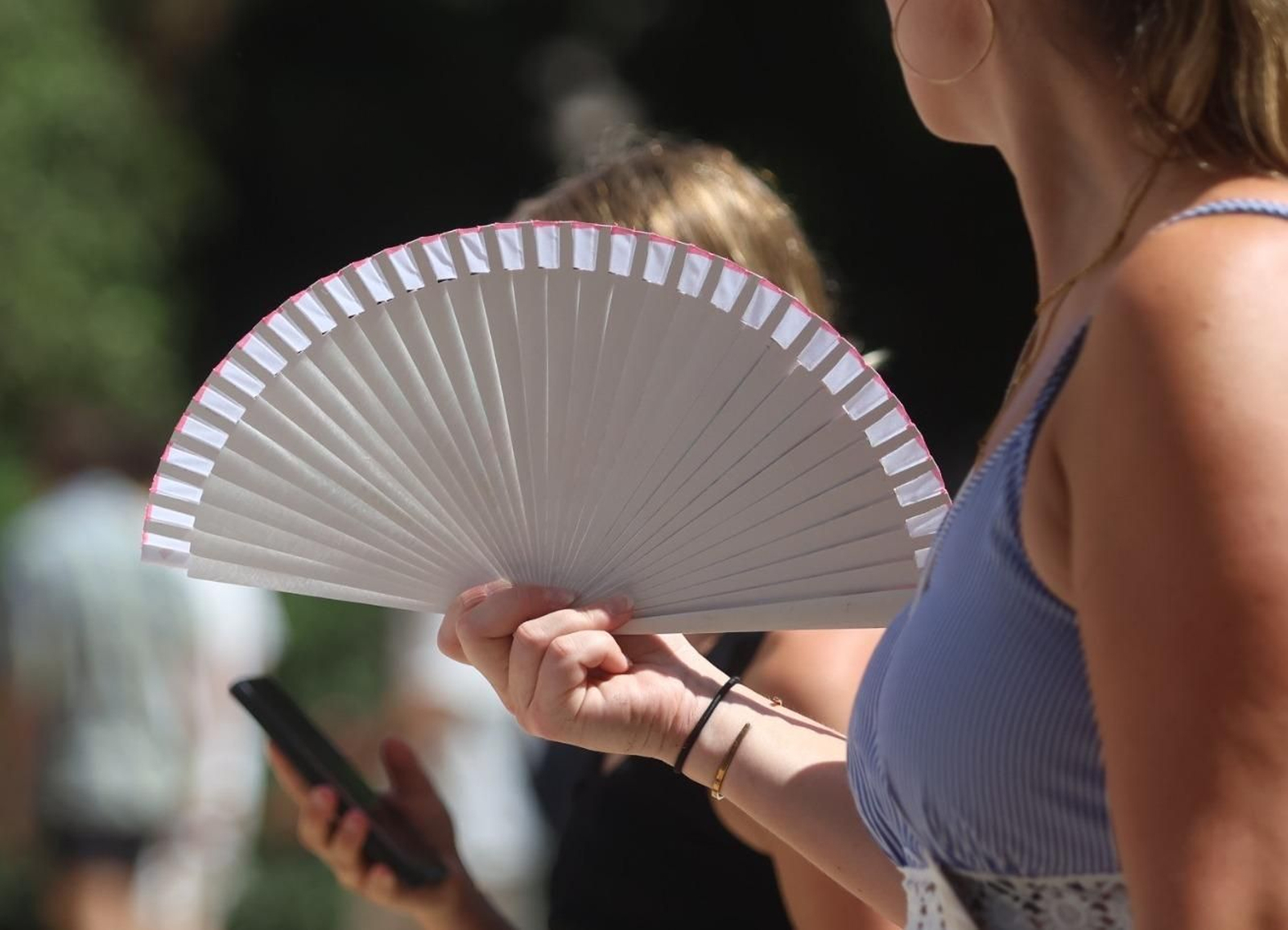 Una mujer hace uso de un abanico para refrescarse