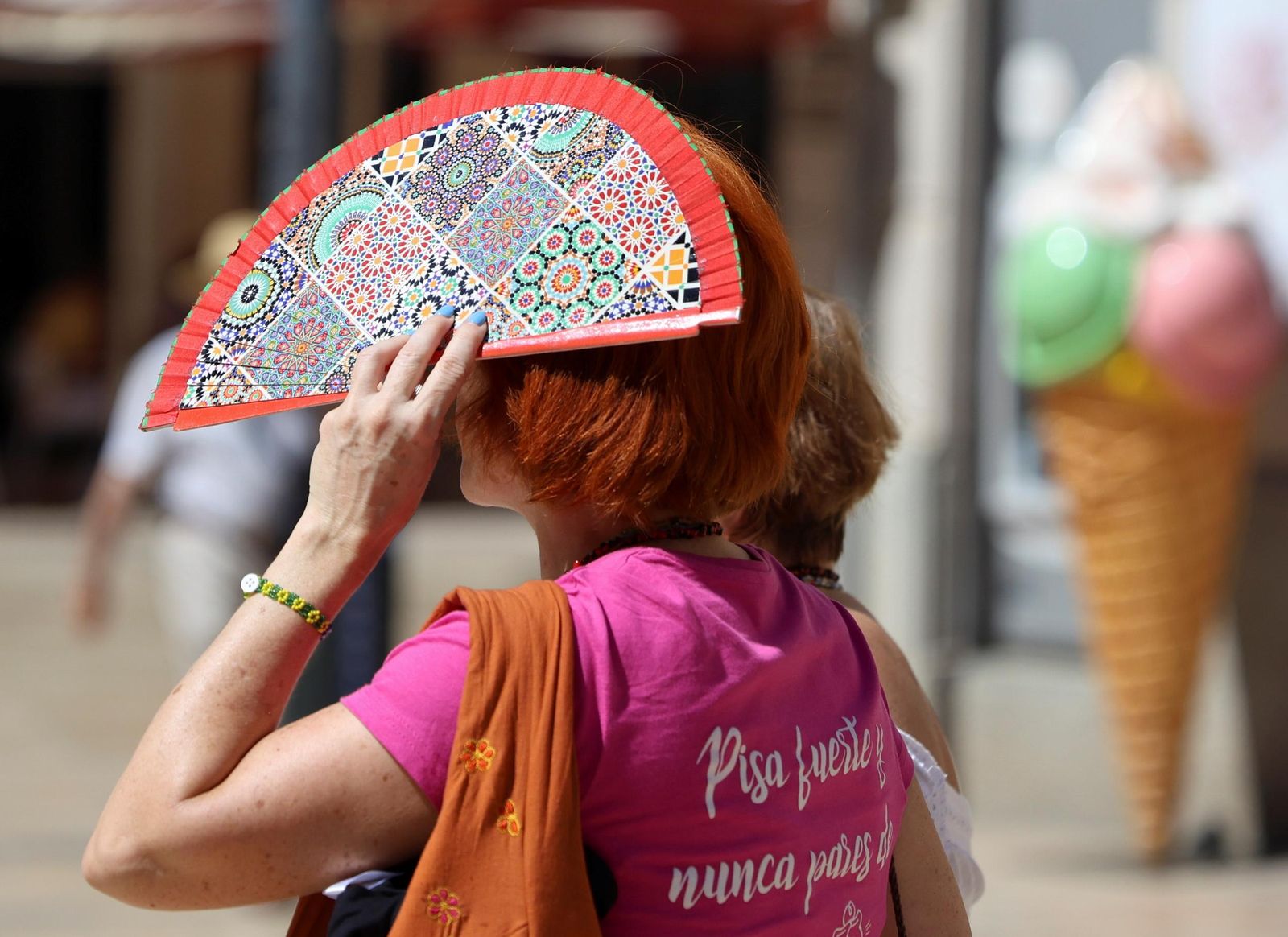 Una mujer se protege del sol con un abanico.