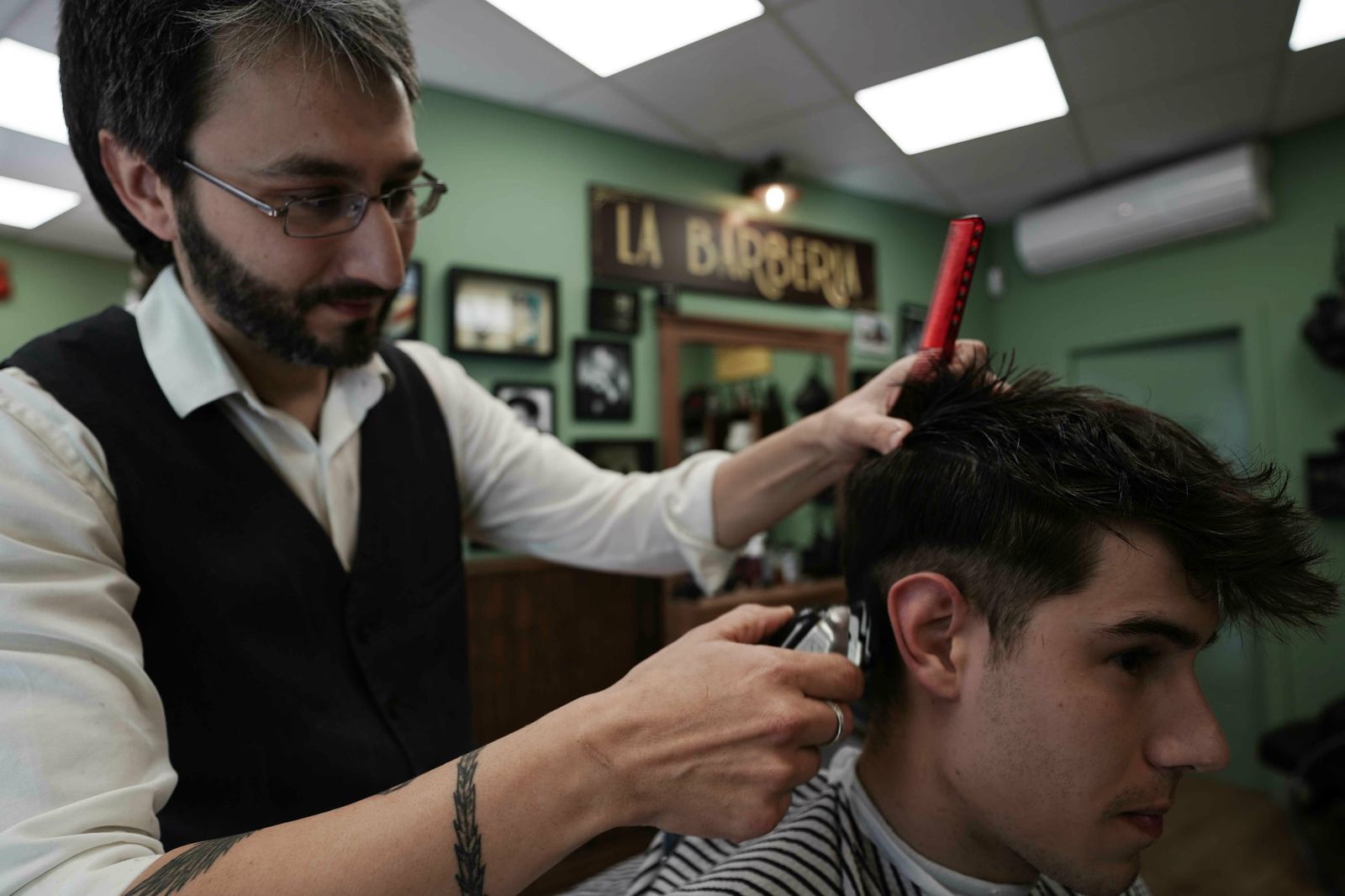 Juan Aguilar realiza un peinado en un cliente.