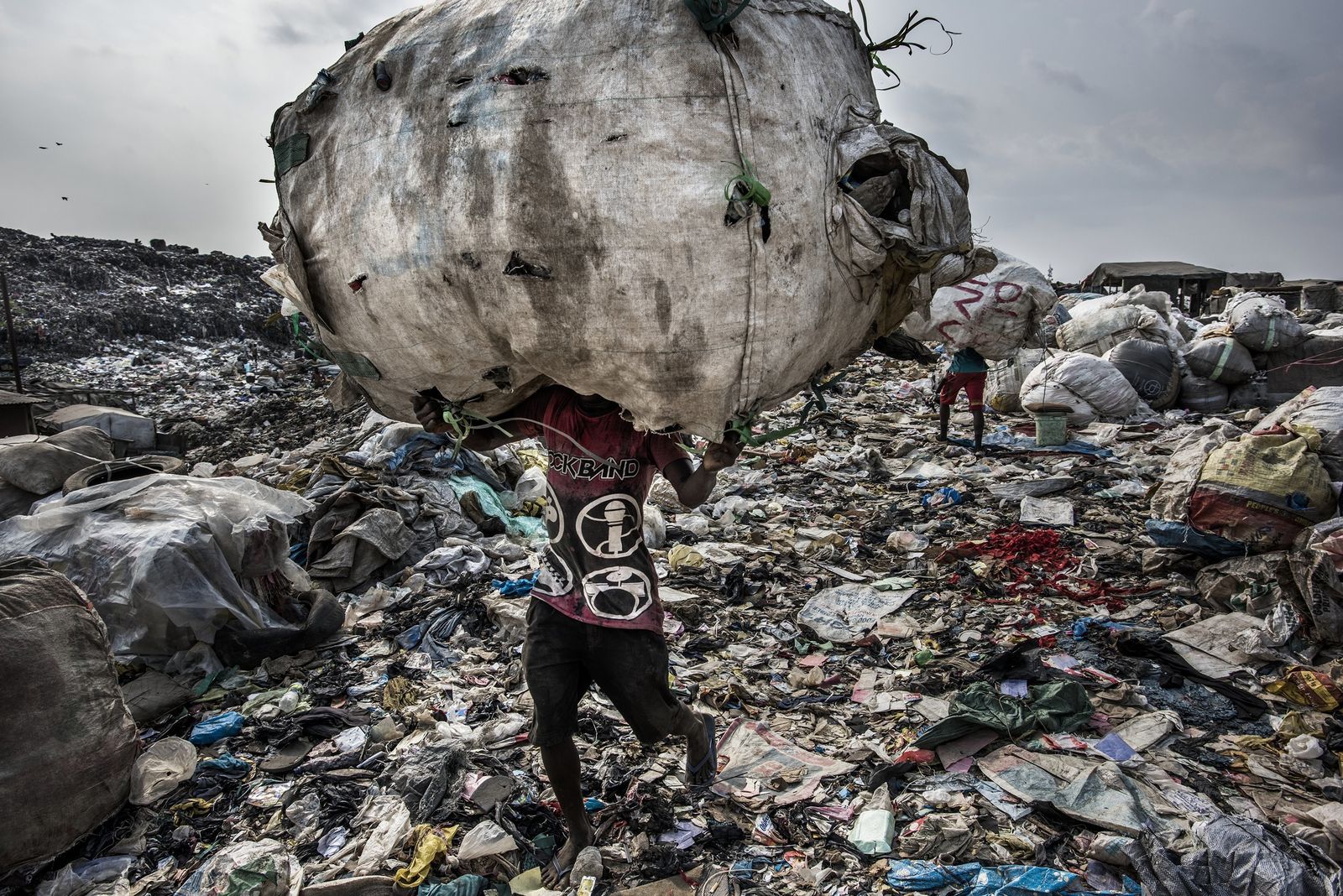 La imagen captada por el fotógrafo Kadir van Lohuizen, ganador del 1er premio de la categoría 'Environment - Stories'. Se ve a  un hombre mientras carga un enorme lomo de botellas recogidas para su reciclaje en el vertedero de Olusosun en Lagos, Nigeria, el 21 de enero de 2017
