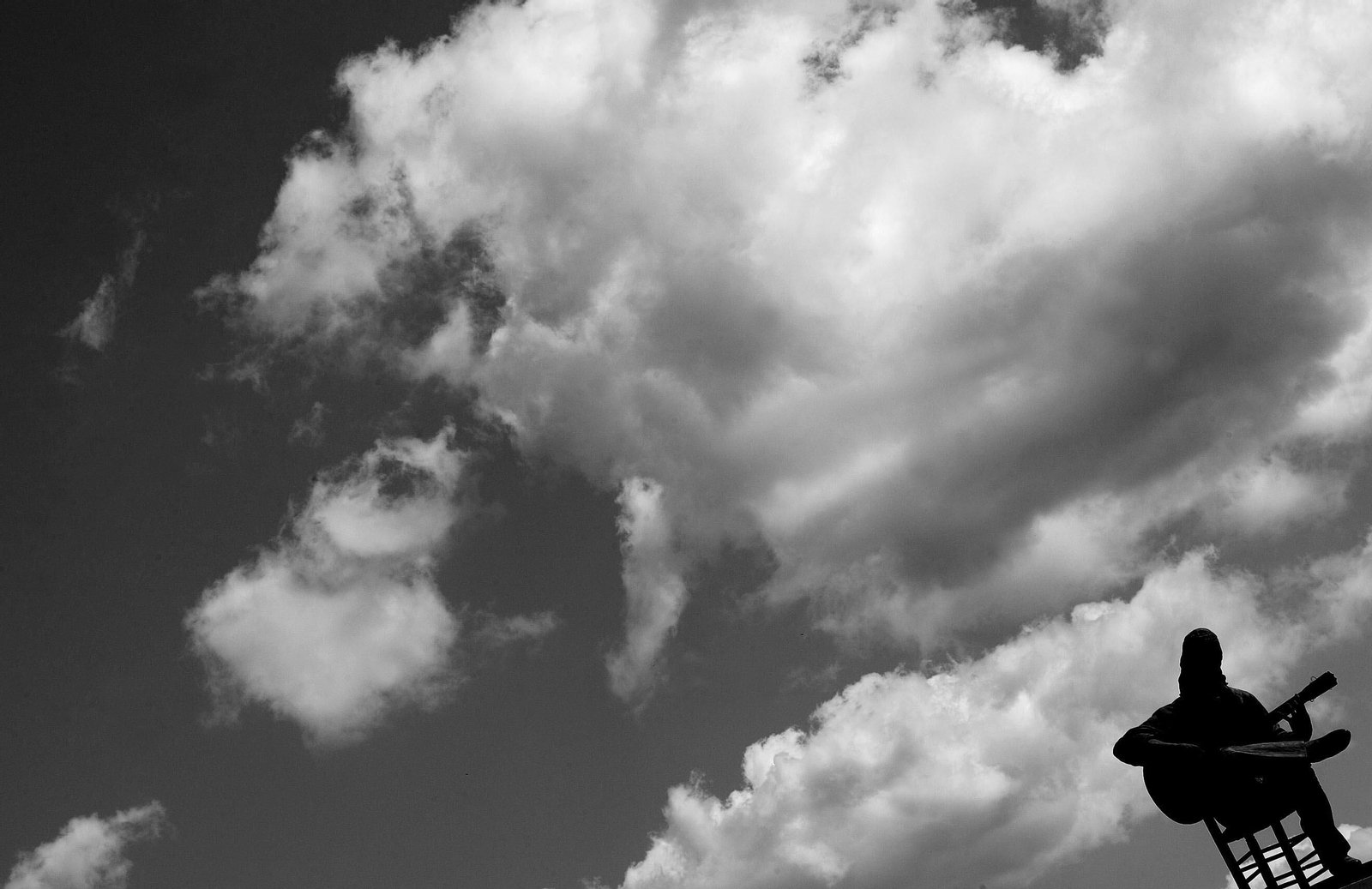 Imagen de la estatua de Paco de  Lucía bajo un cielo nuboso y amenazante.