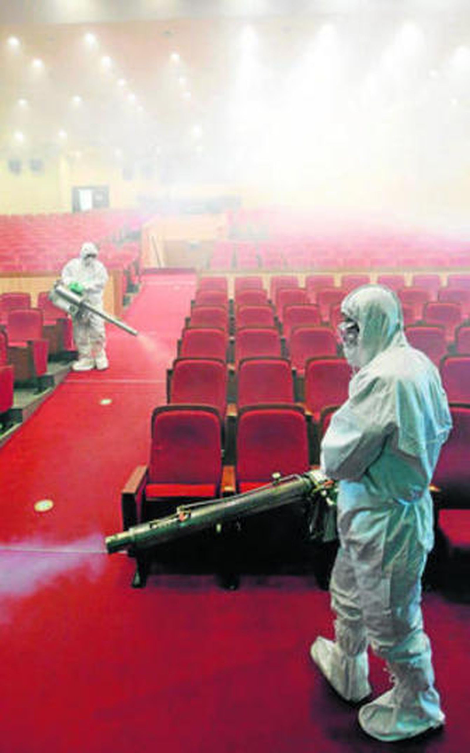 Dos operarios fumigan un salón de actos en Seúl.