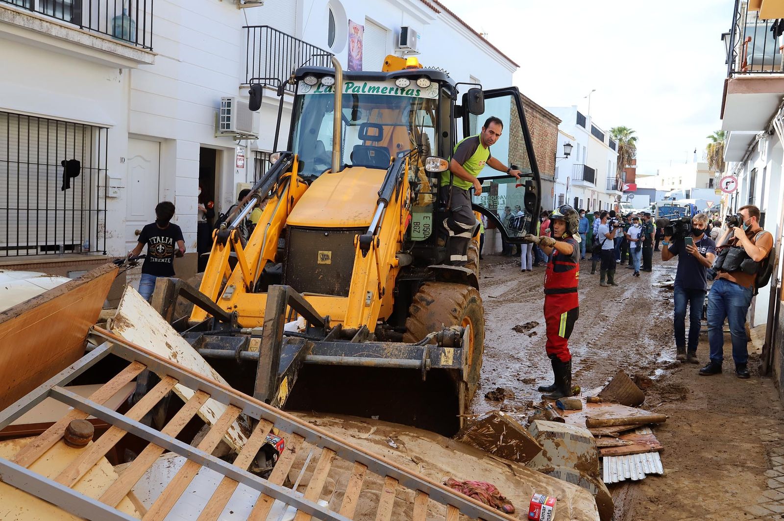 Bomberos del consorcio provincial junto a un operario de maquinaria pesada retiran barro de las calles.