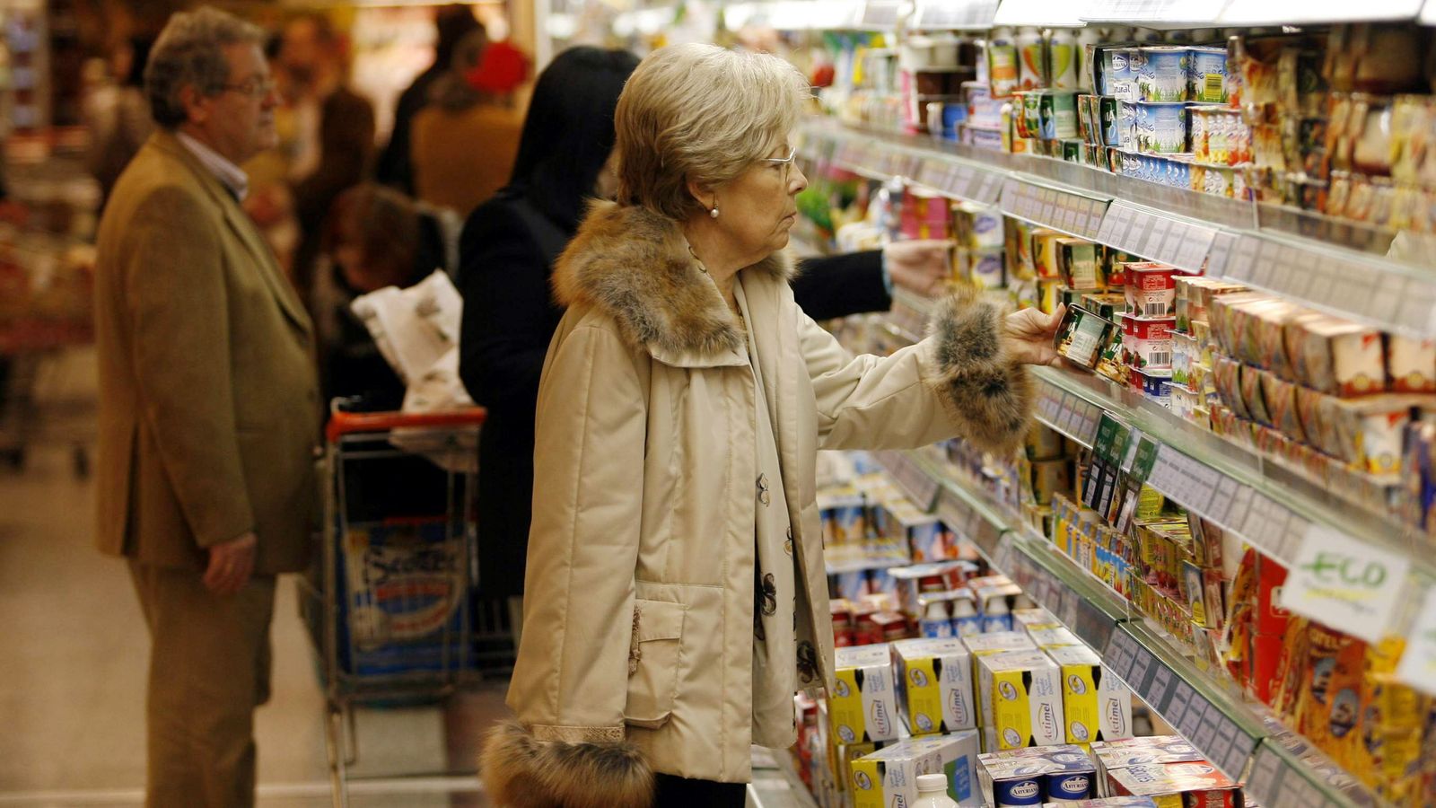 Una mujer mira los alimentos expuestos en una nevera en un supermercado