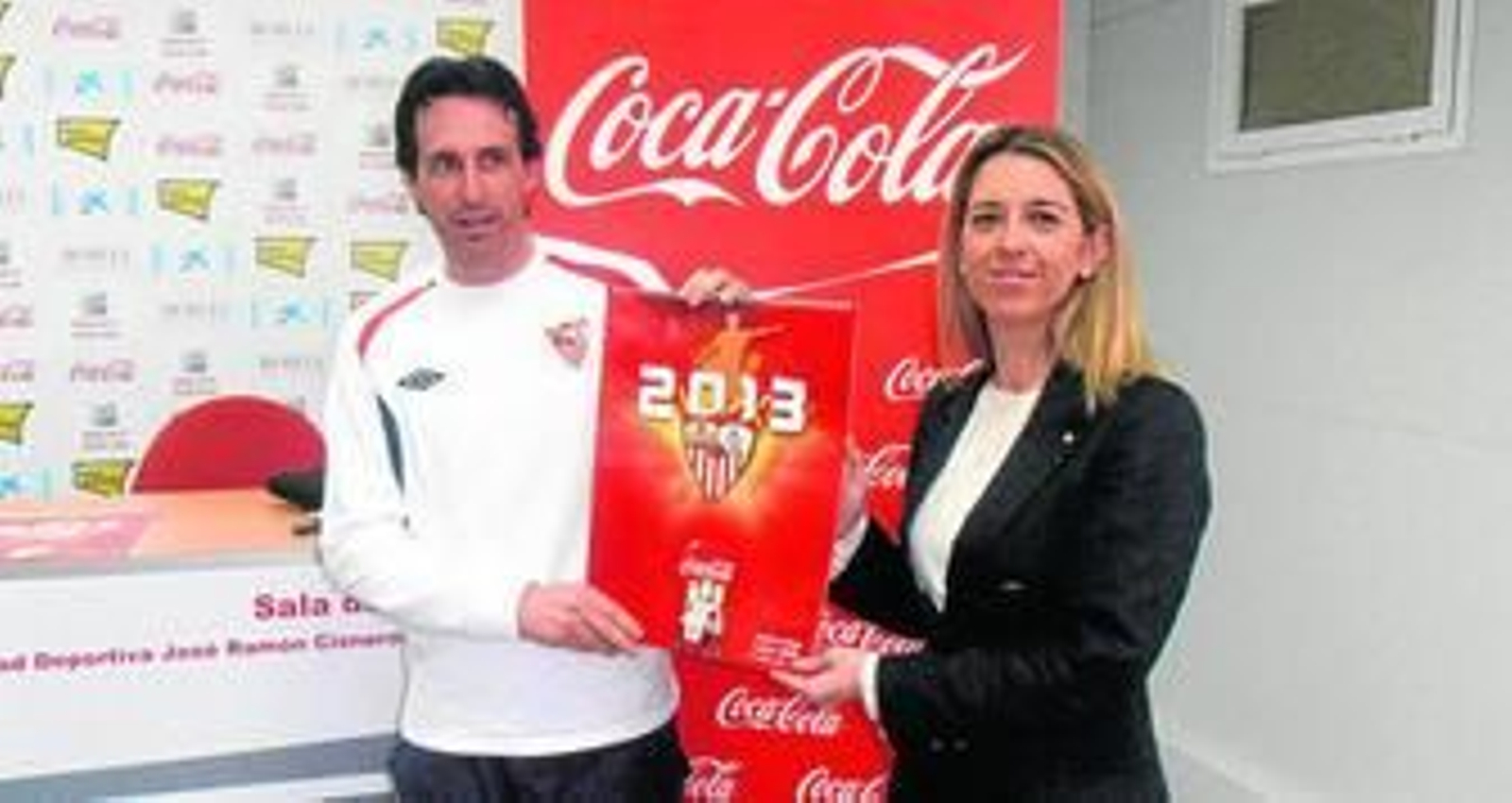 Emery y la representante de Relaciones Externas de Coca-Cola, Ana Millán, con el calendario 2013 que la compañía ha hecho con jugadores del Sevilla.